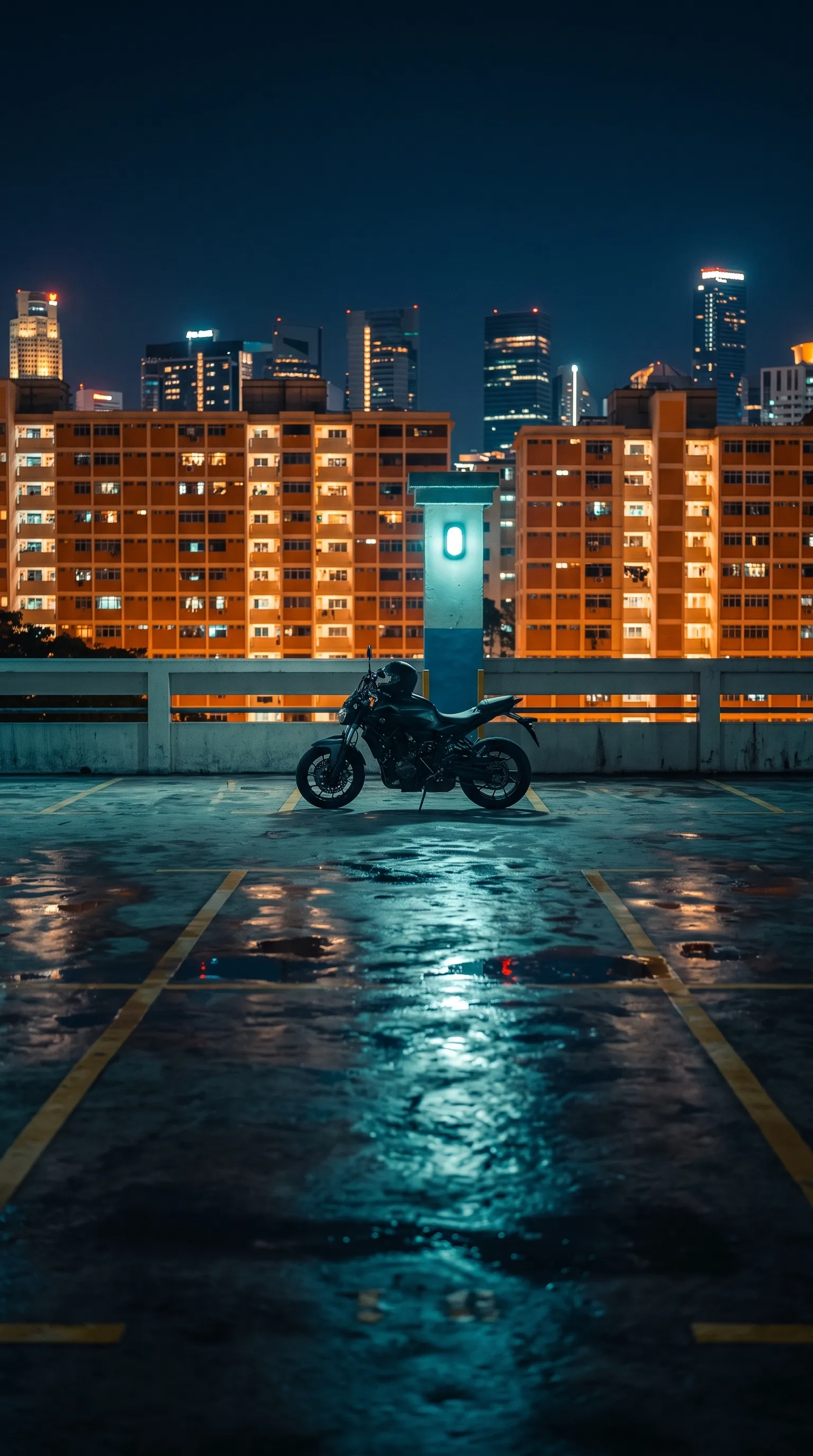 A motorcycle parked on an HDB multi-storey carpark rooftop at night, with lit Singapore housing blocks and the city skyline behind